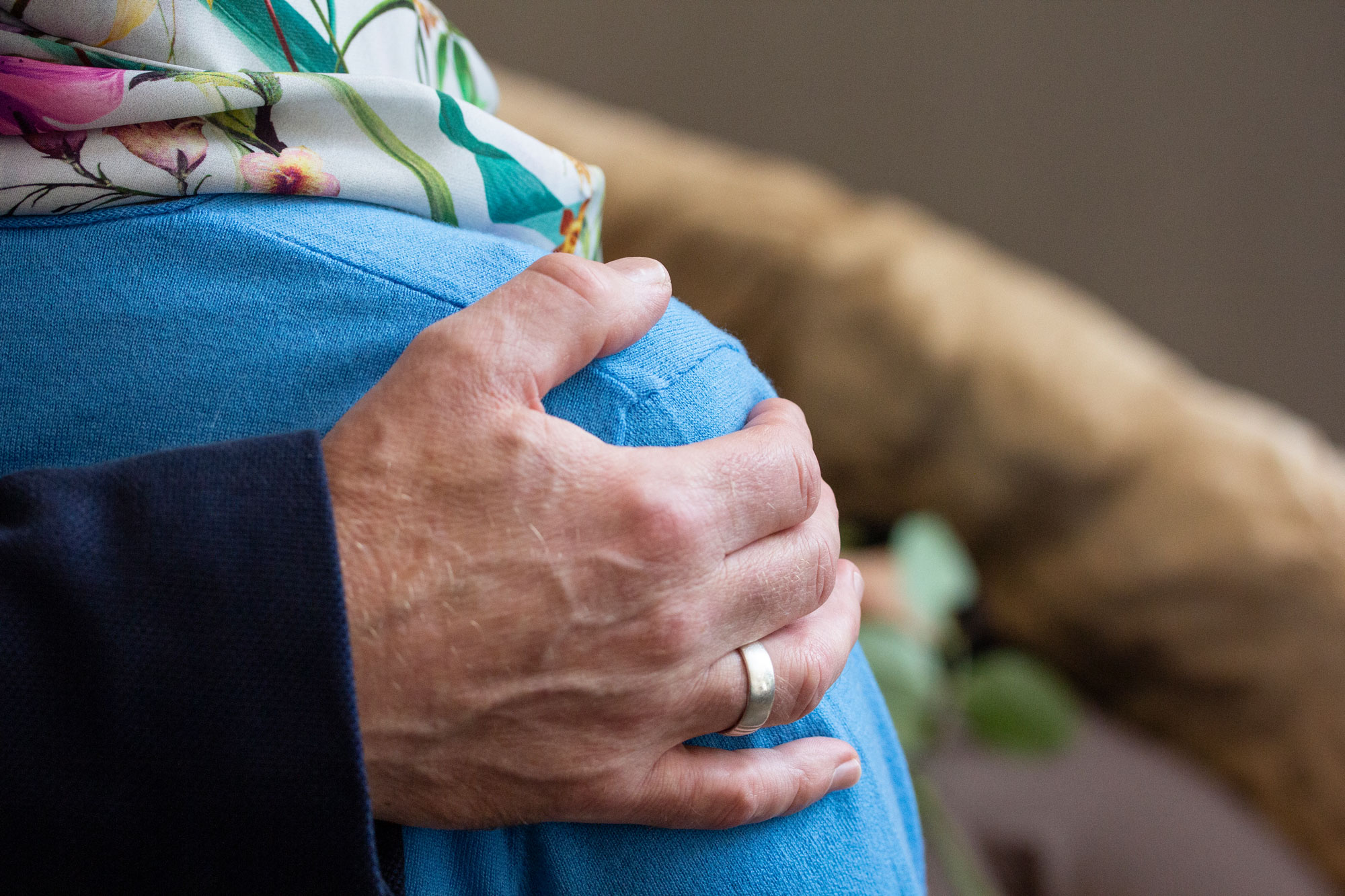 Eine Hand ruht tröstend auf der Schulter einer Person.